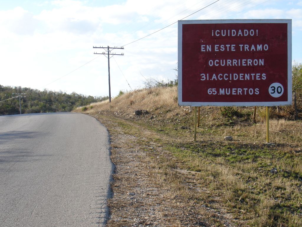 Schon wieder ein Warnschild mit einer Unfallstatistik: Diesmal steht darauf, dass an dieser Stelle 31 Unfälle mit 65 Toten Passiert sind.<br />Dies ist die Stelle, wo man auf der Hauptstraße dem US-Militärlager Gunatanamo Bay am nächsten kommt, etwa sechs bis acht Kilometer. Näher heran kommt man nur mit Sondergenehmigung. Alle Zufahrten sind vom kubanischen Militär bewacht.